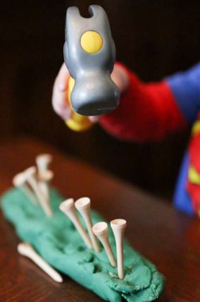 Hammering tees into play dough for toddlers to work on hand and eye coordination