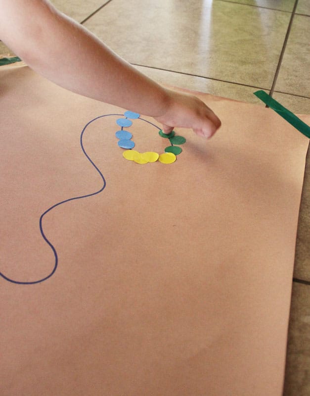 Tape down the large piece of paper, draw a wacky design with the marker, and then provide the stickers to trace the design. 