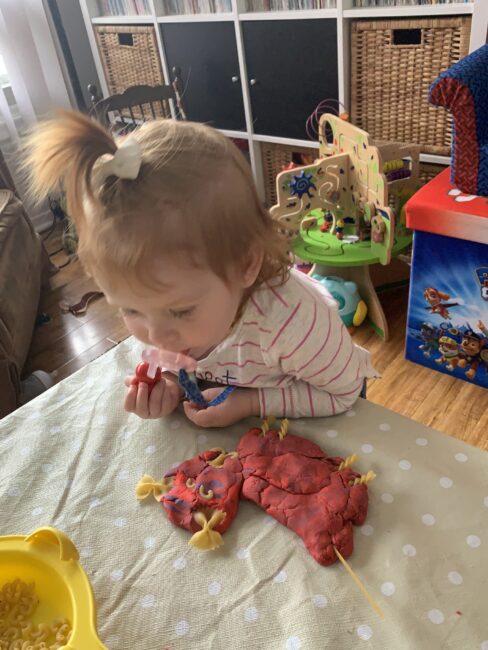 My toddler admiring the complete family portraits made with play dough and pasta!