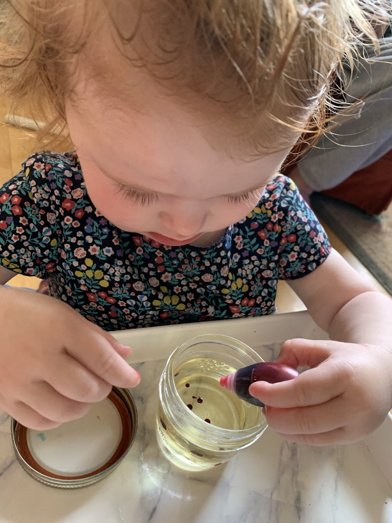 Fine motor practice squeezing food coloring drops into small jars of oil.